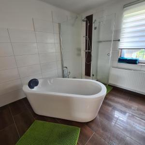 a white bath tub in a bathroom with green rugs at Ferienwohnung Claudia in Altossiach
