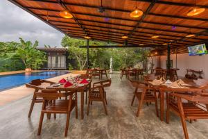 um restaurante com mesas e cadeiras de madeira e uma piscina em Atha Resort em Sigiriya