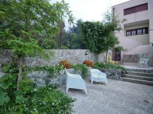 un patio con 2 sillas blancas y una pared en GuimaraesLiving - Hostel & Adventure, en Guimarães