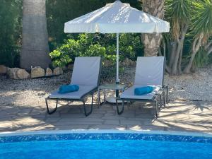 two chairs and an umbrella next to a pool at Villa Ambios in Peyia