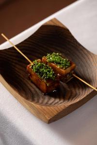 two pieces of food on a wooden plate with chopsticks at Mingary Castle - Restaurant with Rooms in Kilchoan