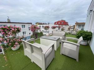 a balcony with white chairs and tables and flowers at Pod Aniołem in Mielno