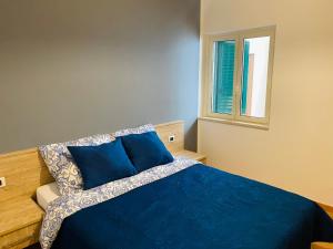 a bedroom with a blue bed and a window at Marina Apartament in Scalea