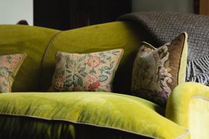 a green couch with several pillows on it at Mingary Castle - Restaurant with Rooms in Kilchoan