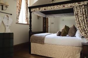 a bedroom with a canopy bed with white sheets and pillows at Mingary Castle - Restaurant with Rooms in Kilchoan