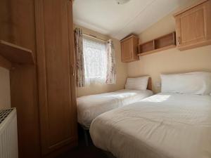 Un dormitorio pequeño con dos camas y una ventana. en Contemporary Caravan at Newquay Holiday Park, en Newquay 45 fotos más
