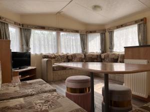 een woonkamer met een tafel en een bank bij Contemporary Caravan at Newquay Holiday Park in Newquay