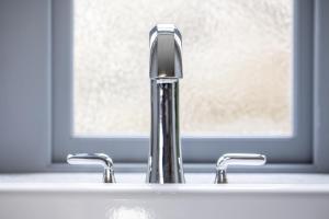 a bathroom sink with two faucets and a window at Mingary Castle - Restaurant with Rooms in Kilchoan