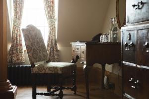 a room with a chair and a dresser and a window at Mingary Castle - Restaurant with Rooms in Kilchoan