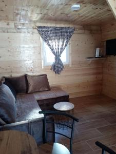 Sala de estar de una cabaña de madera con sofá y ventana en Holiday_home _Jana, en Žabljak