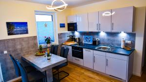 a kitchen with white cabinets and a table with a sink at Elegantes & modernes Apartment NeLi mit Terrasse, 100m zum Hafen Röbel Müritz in Röbel