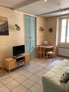uma sala de estar com uma televisão e uma mesa em Studio cosy au coeur de Saint Martin Vésubie em Saint-Martin-Vésubie
