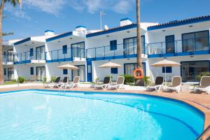 una piscina frente a un hotel con sillas y sombrillas en Alsol Los Caribes 1, en Playa del Inglés