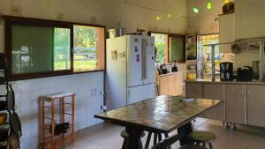 a kitchen with a table and a white refrigerator at Sítio Cumuru in Paraty