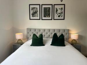 a white bed with two green pillows and two lamps at Castle Hotel in Eynsford