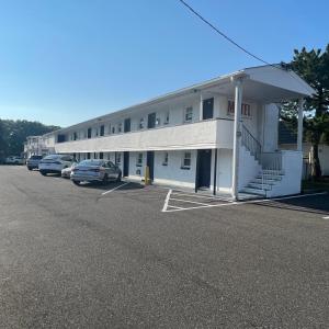 een groot wit gebouw met auto's geparkeerd op een parkeerplaats bij Budget Inn Motel Suites Somers Point in Somers Point