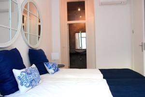 um quarto com uma cama com almofadas azuis e brancas em Lisbon Coral Apartment em Lisboa