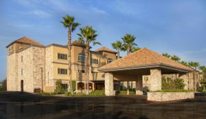 a large building with palm trees in front of it at Ayres Suites Diamond Bar in Diamond Bar