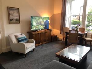 uma sala de estar com uma televisão de ecrã plano e uma mesa em Lovely 3 bedroom family friendly cottage in North Berwick em North Berwick