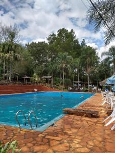 a swimming pool with blue water and white chairs at Complejo Don Raúl in Puerto Rico