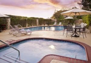 a swimming pool with chairs and a table and an umbrella at Ayres Suites Ontario at the Mills Mall - Rancho Cucamonga in Ontario