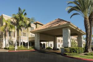 a large building with palm trees in front of it at Ayres Suites Mission Viejo - Lake Forest in Mission Viejo