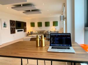 a laptop sitting on a wooden table in a living room at Beautiful modern sea-side apartment in the city in Edinburgh