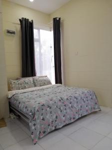 - une chambre avec un lit doté d'un couvre-lit floral et d'une fenêtre dans l'établissement Teratak Sherra Roomstay, à Macang