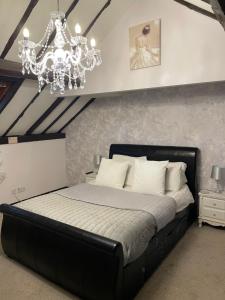 a bedroom with a black bed with a chandelier at Coach house hotel in Royston