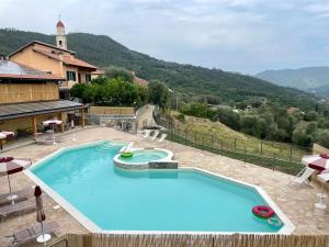 a large blue swimming pool with a hill in the background at Agriturismo Gli Ulivi in Garlenda