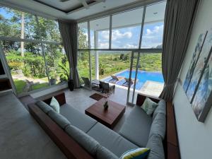 a living room with a couch and a large window at Villa di Bias in Tirtagangga