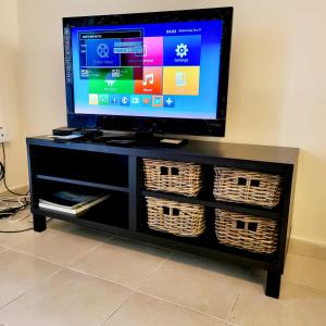 a flat screen tv on a black entertainment center with baskets at Paphos town house vacation in Paphos City