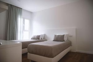 a white room with two beds and a window at Vilas do Olival in Ponta Delgada +19 photos