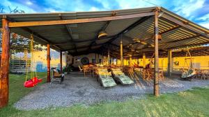 a pavilion with chairs and tables and a swing at Restaurante & Pousada Portal dos Ventos in Icapuí