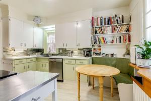 cocina con armarios blancos y mesa de madera en Four Bedroom Rosedale Home en Toronto