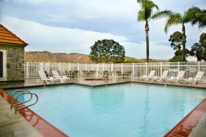 安納海姆的住宿－約巴林達/阿納海姆山艾瑞斯套房酒店，一个带椅子和棕榈树的大型游泳池