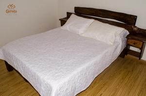 a bed with white sheets and a wooden headboard at HOTEL COLONIAL VILLA CARMELA in Tota