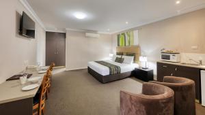 Habitación de hotel con cama, mesa y sillas en Drovers Motor Inn, en Dalby