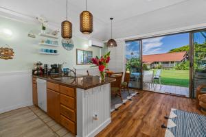 a kitchen with a kitchen island and a living room at Quiet Kiahuna plantation , New Remodel with AC in Koloa
