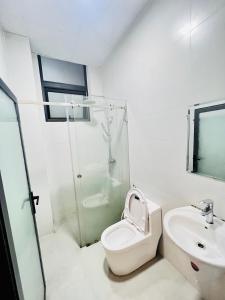 a white bathroom with a toilet and a sink at Dalat Family Hostel in Da Lat