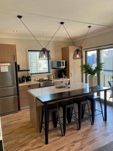 uma cozinha com uma mesa preta e uma cozinha com um frigorífico em Cardrona Ski Apartment em Wanaka