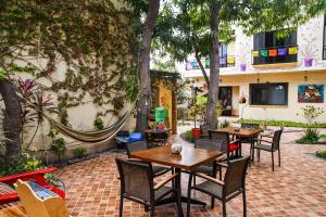 un patio al aire libre con mesas, sillas y árboles en Hotel Casa Mangos Loreto en Loreto