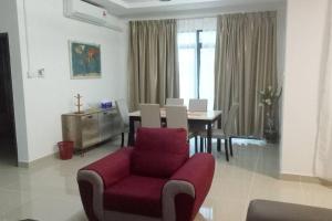 a living room with a red chair and a table at Semi D Pengerang Johor in Kampong Gambut