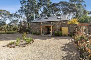 a stone house with a garage in a yard at Woodlands Retreat in Ocean Grove