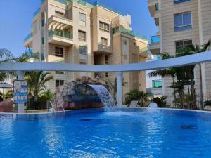a swimming pool with a fountain in front of a building at EILAT GOLF RESIDENCE Apartment A 1 in Eilat