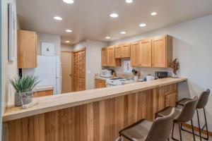 a kitchen with wooden cabinets and a counter with chairs at Pelicans Nest - Meredith Lodging in Pacific City +25 photos