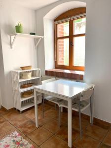 - une table et des chaises blanches dans une chambre avec fenêtre dans l'établissement Suterena w centrum Mrągowa, à Mrągowo