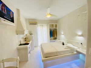 a white bedroom with a bed and a kitchen at Deluxe Studios & Suites Ageri-Milos in Adamantas