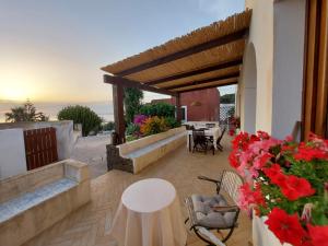 a patio with red flowers and a table and chairs at Birbiciù mare in Pantelleria