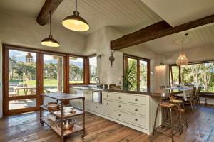 a kitchen with a table and some chairs and windows at Kanuka Terrace - Luxury Strawbale House in Kaikoura